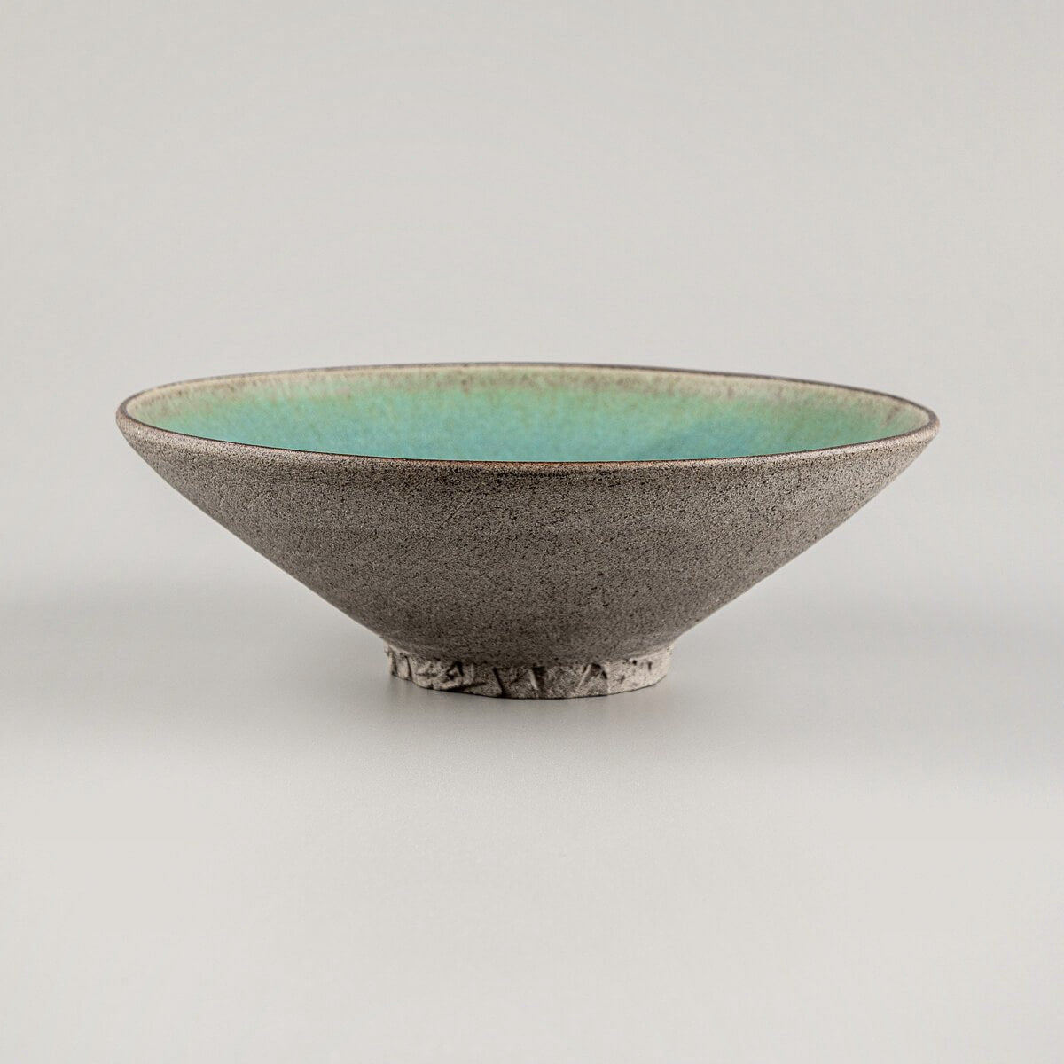 Side profile of artisanal ceramic plate with unglazed textured exterior.
