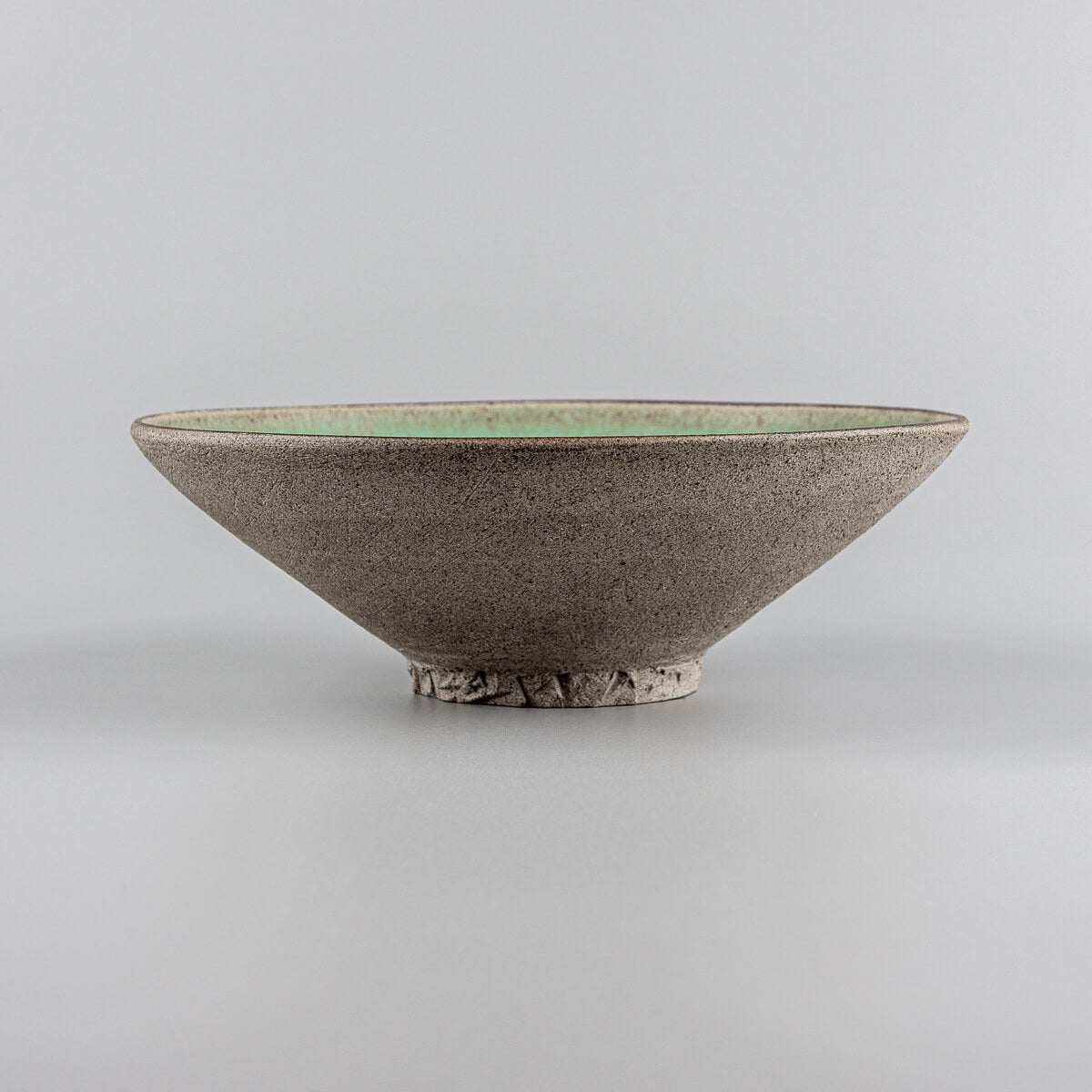 Artisan stoneware plate with carved base, ideal for gourmet cuisine.