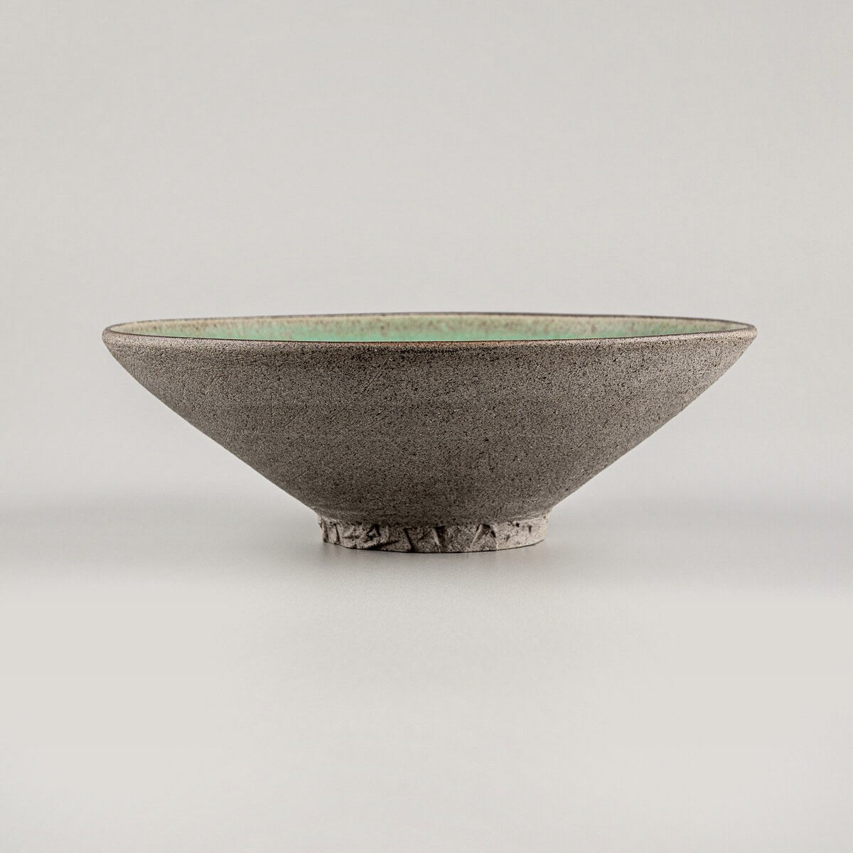 Artisan stoneware plate with carved base, ideal for gourmet cuisine.