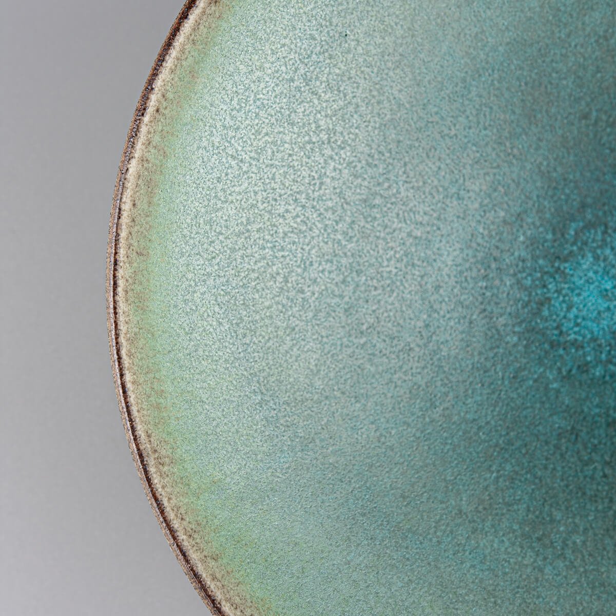 Close-up of matte turquoise glazed ceramic plate surface.