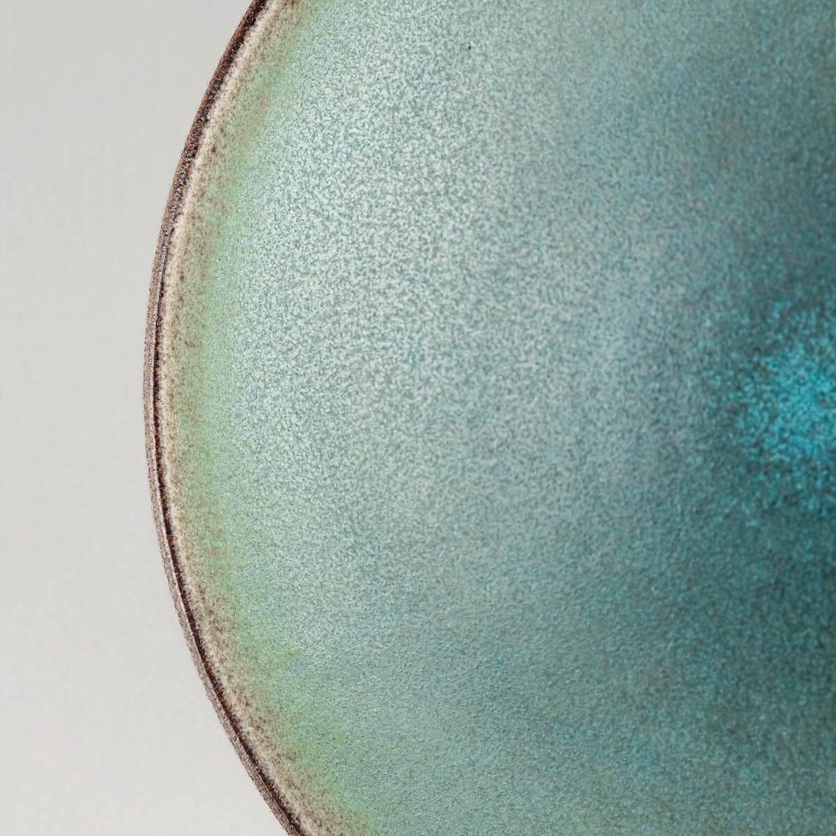Close-up of matte turquoise glazed ceramic plate surface.
