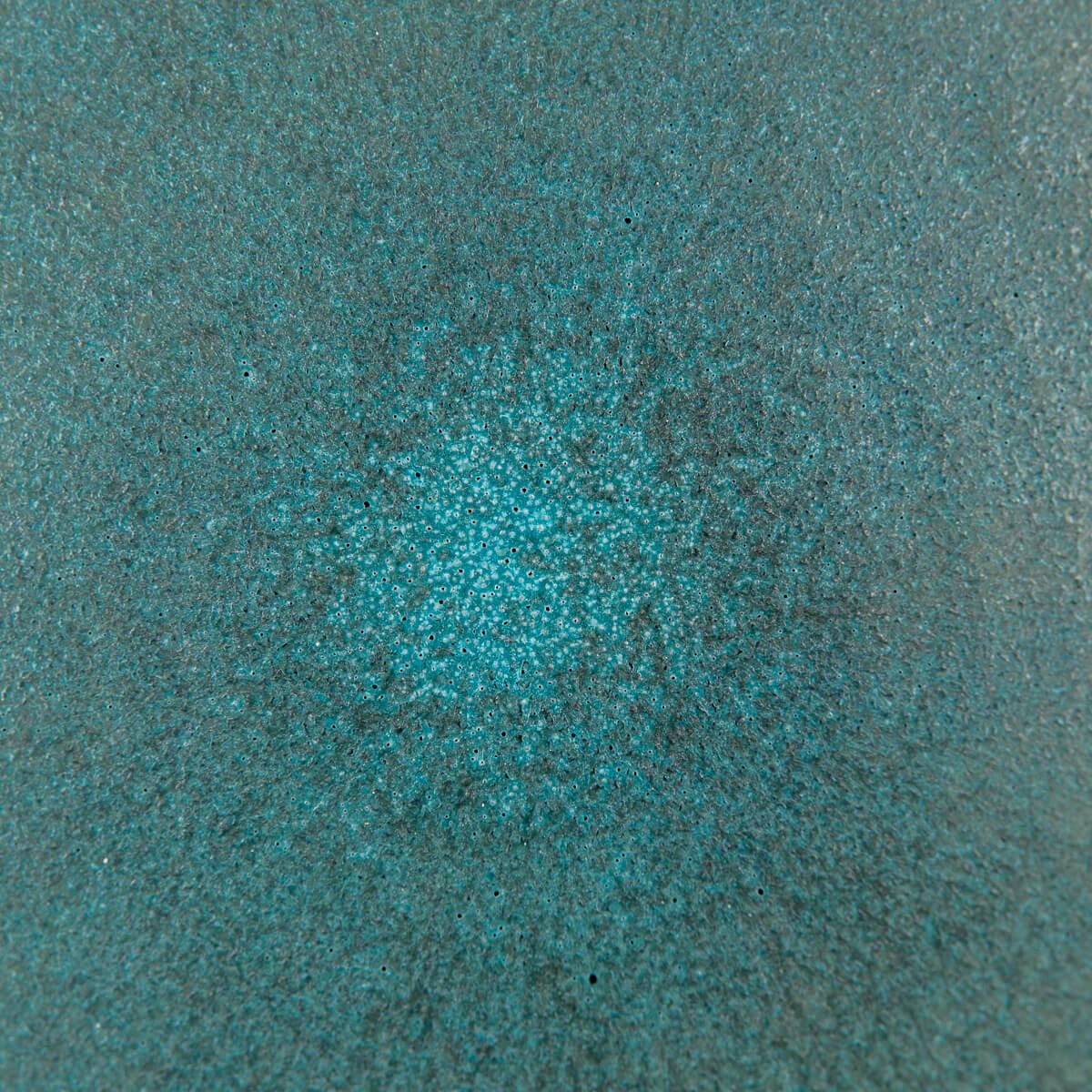 Detailed view of handcrafted ceramic plate interior with vibrant glaze tones.