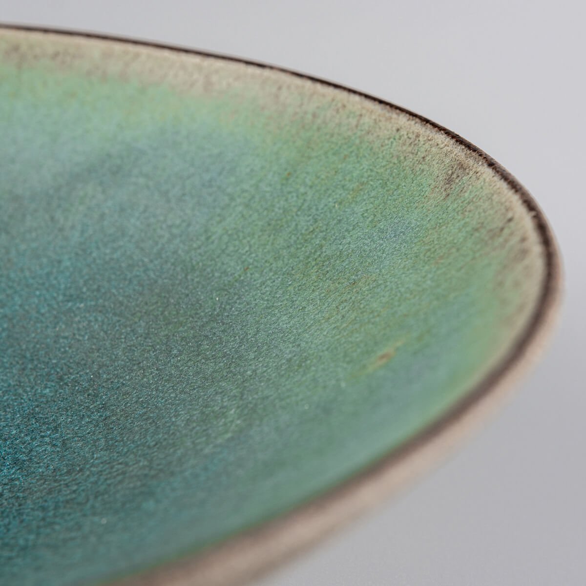 Fine dining ceramic plate with turquoise interior and raw clay edge.