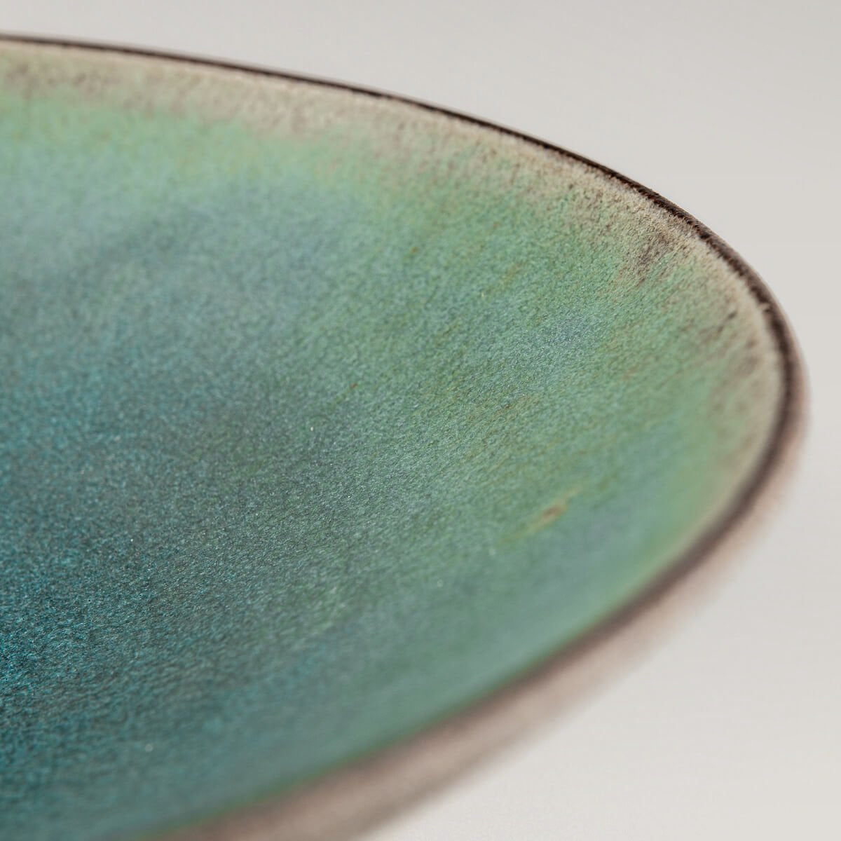 Fine dining ceramic plate with turquoise interior and raw clay edge.