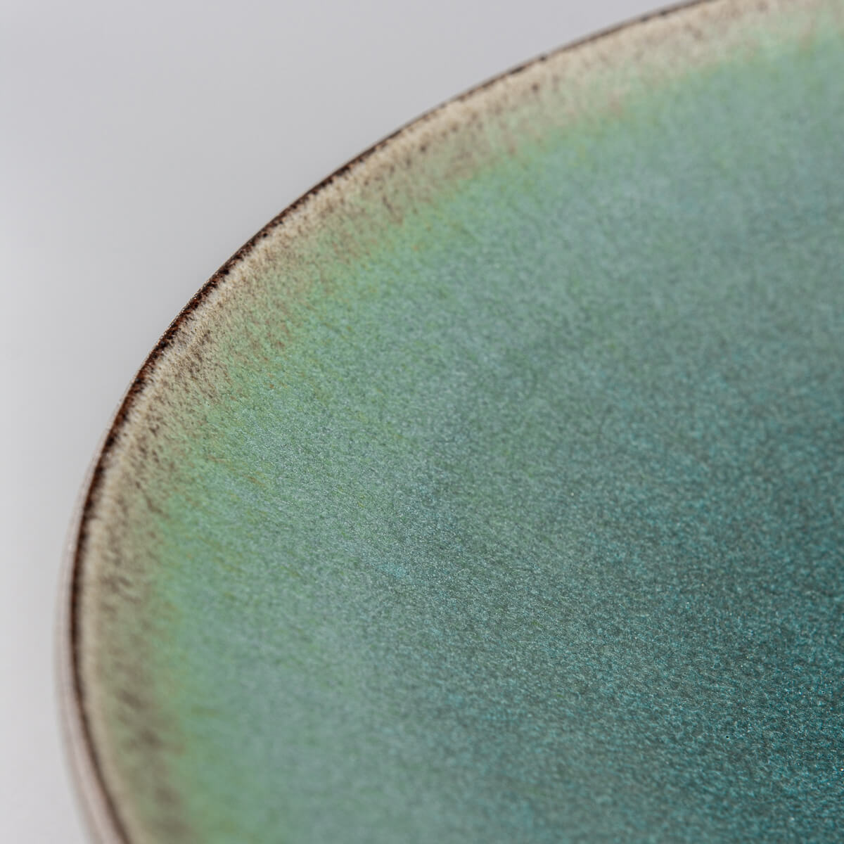 Detail of turquoise glazed handmade ceramic plate for sophisticated table settings.