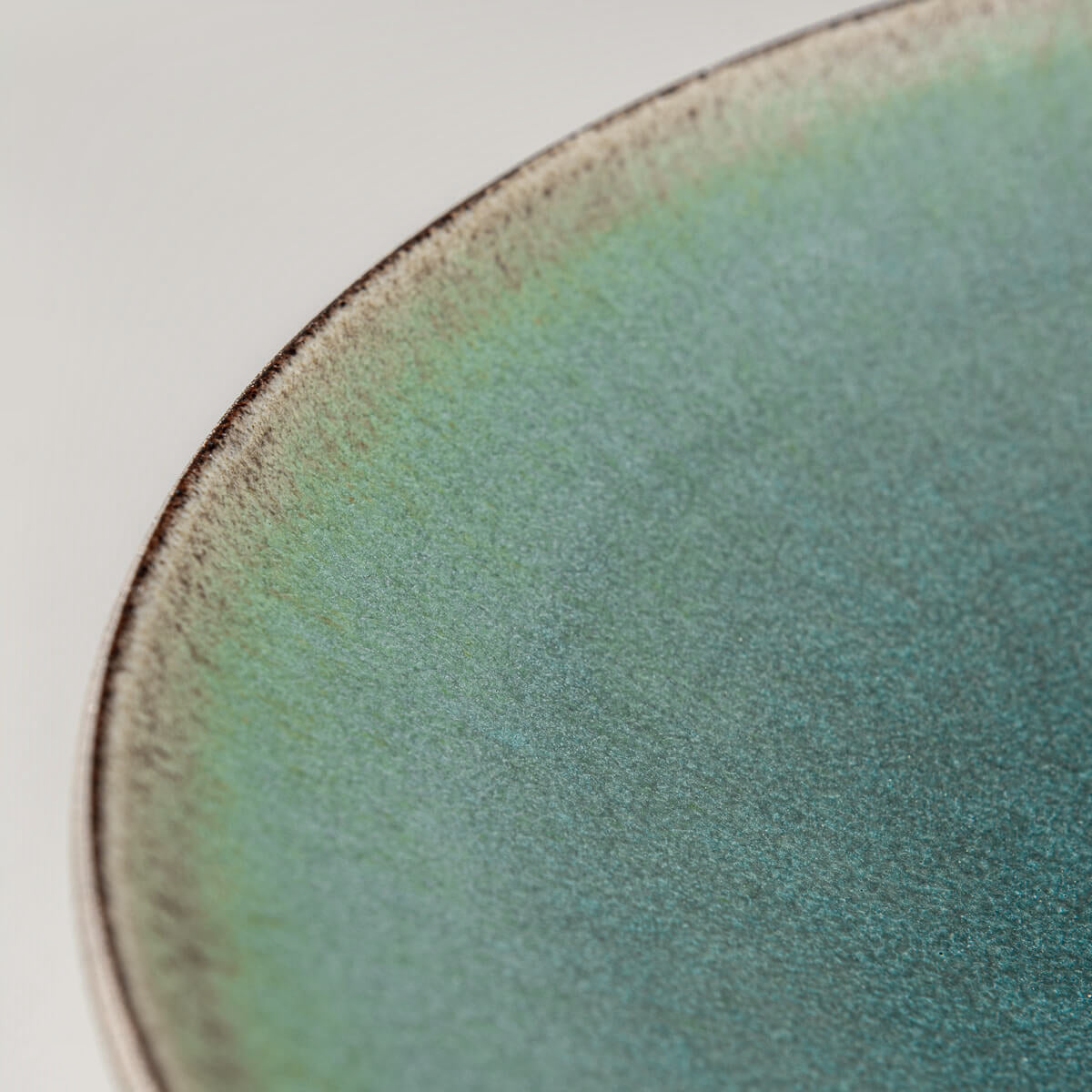 Detail of turquoise glazed handmade ceramic plate for sophisticated table settings.