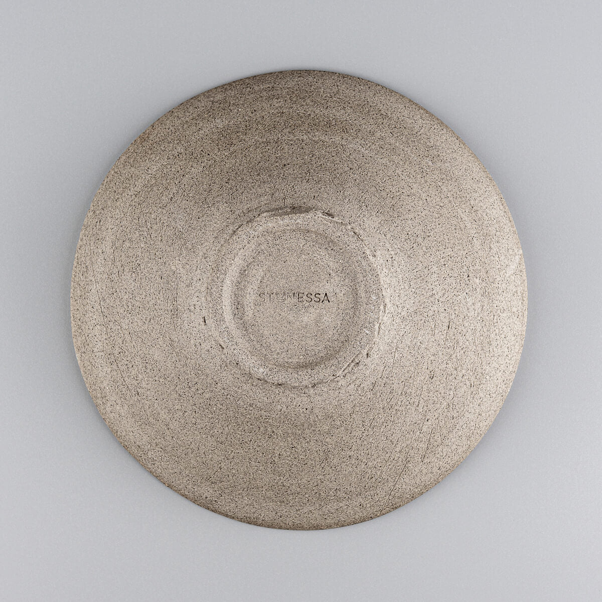 Base of handcrafted ceramic plate highlighting textured unglazed finish.