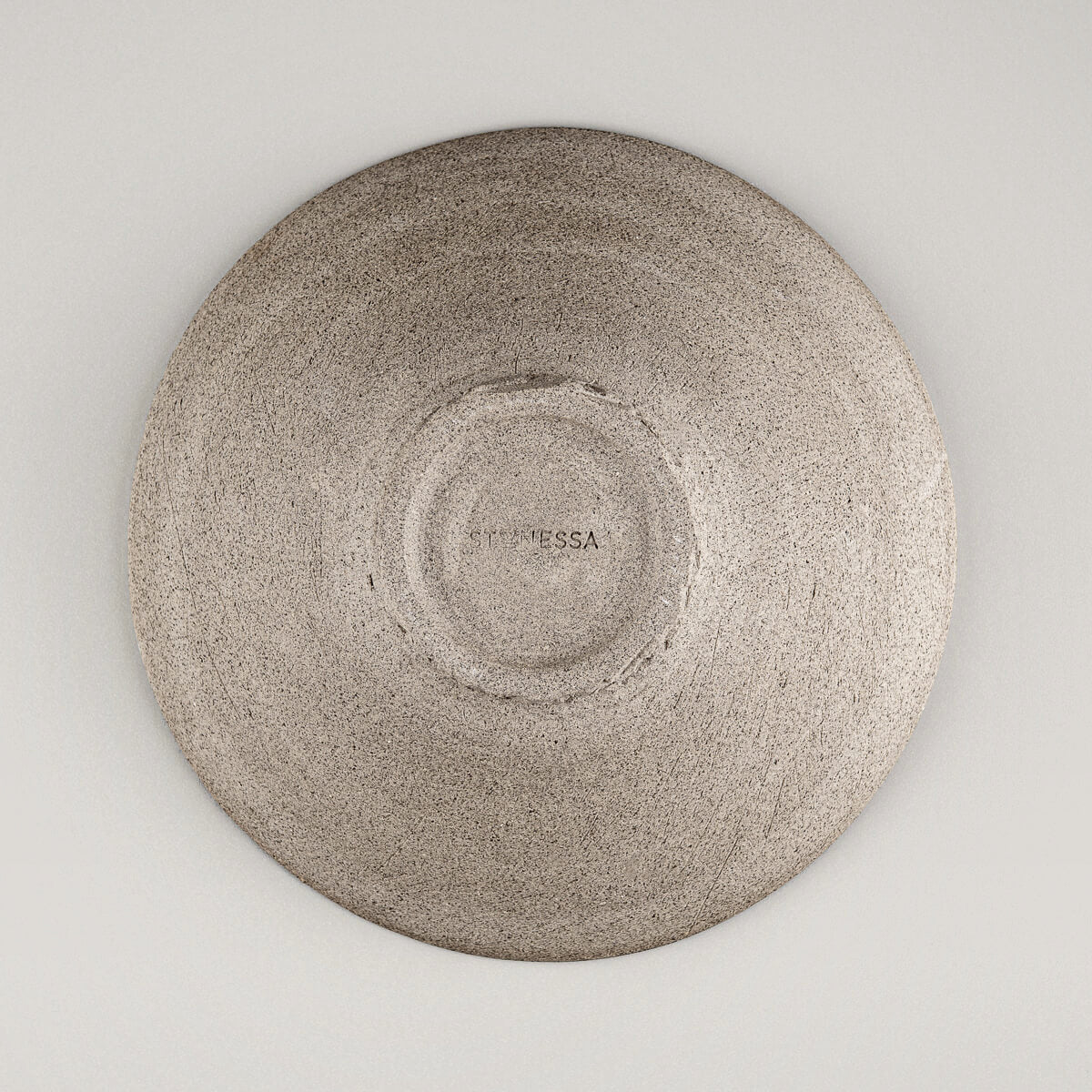 Base of handcrafted ceramic plate highlighting textured unglazed finish.