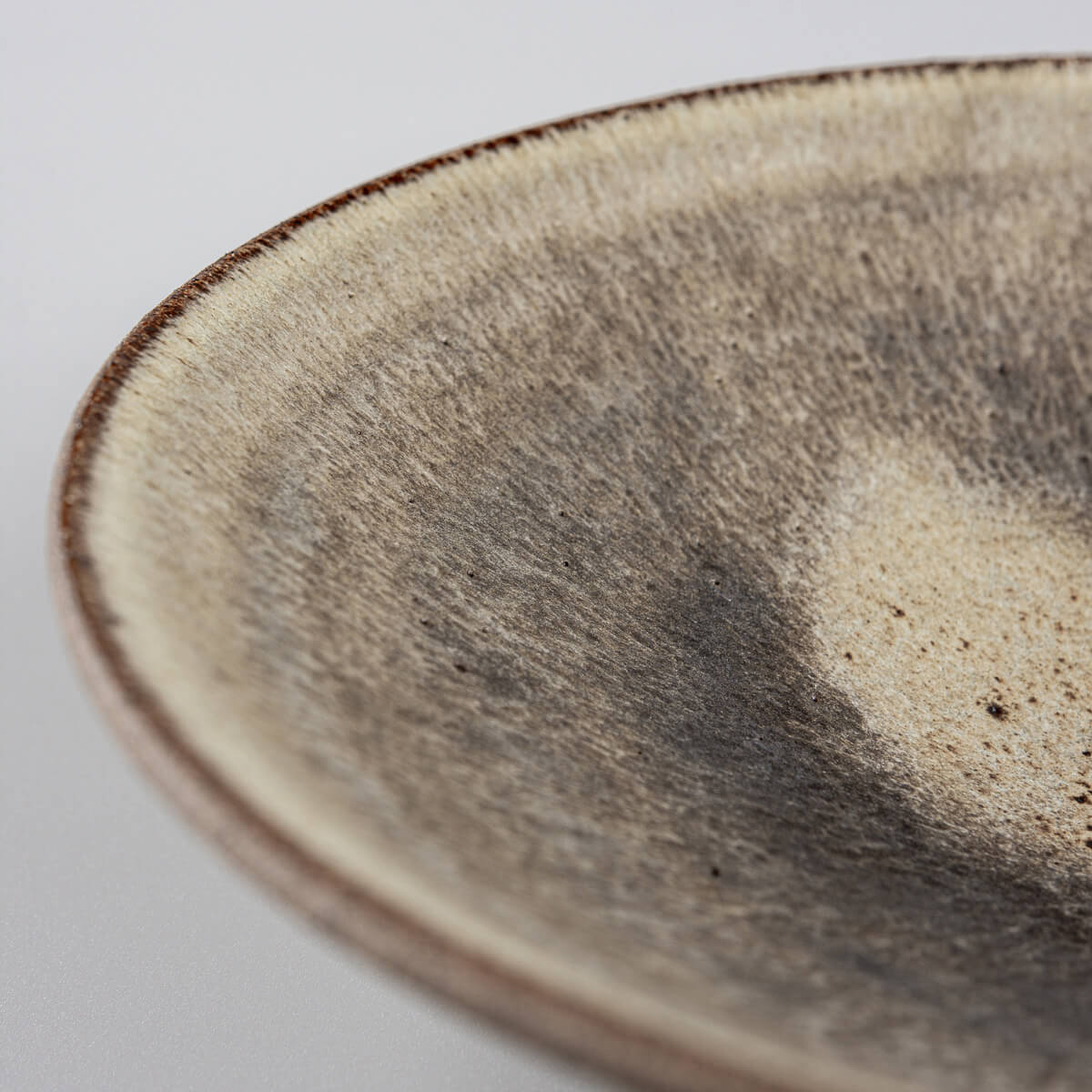 Side view of fine dining ceramic dinner plate with earthy tones and artisanal finish.