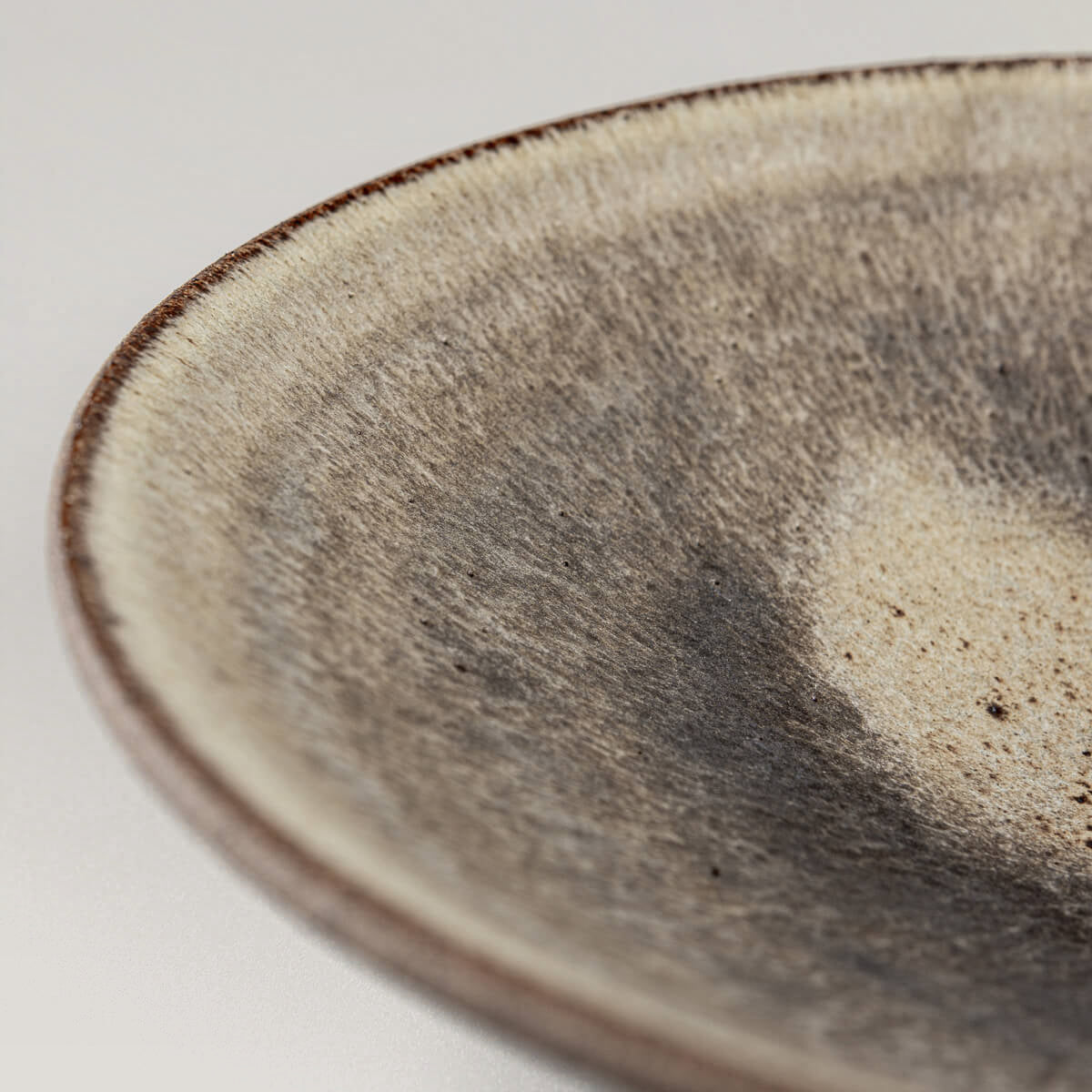 Side view of fine dining ceramic dinner plate with earthy tones and artisanal finish.