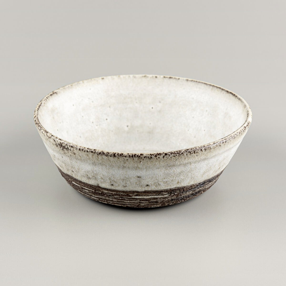 Side angle of artisanal stoneware bowl with carved horizontal lines and raw clay finish.