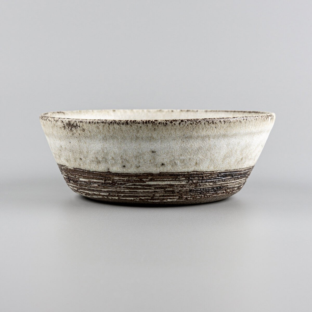 Detail of unglazed lower section with carved texture on handmade pottery bowl.