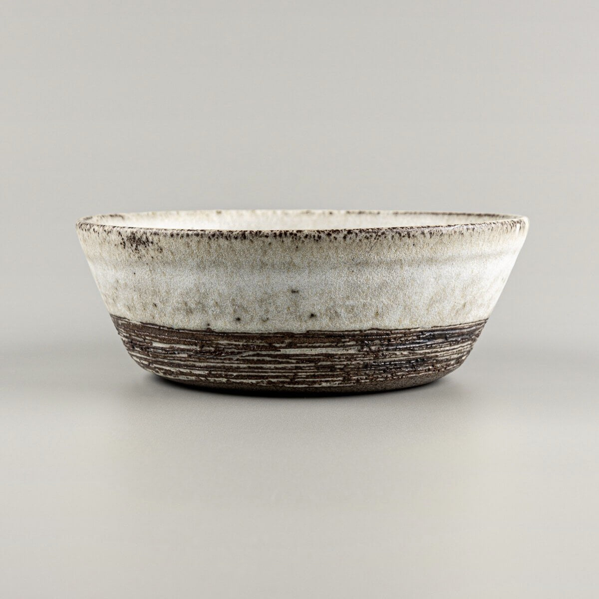 Detail of unglazed lower section with carved texture on handmade pottery bowl.