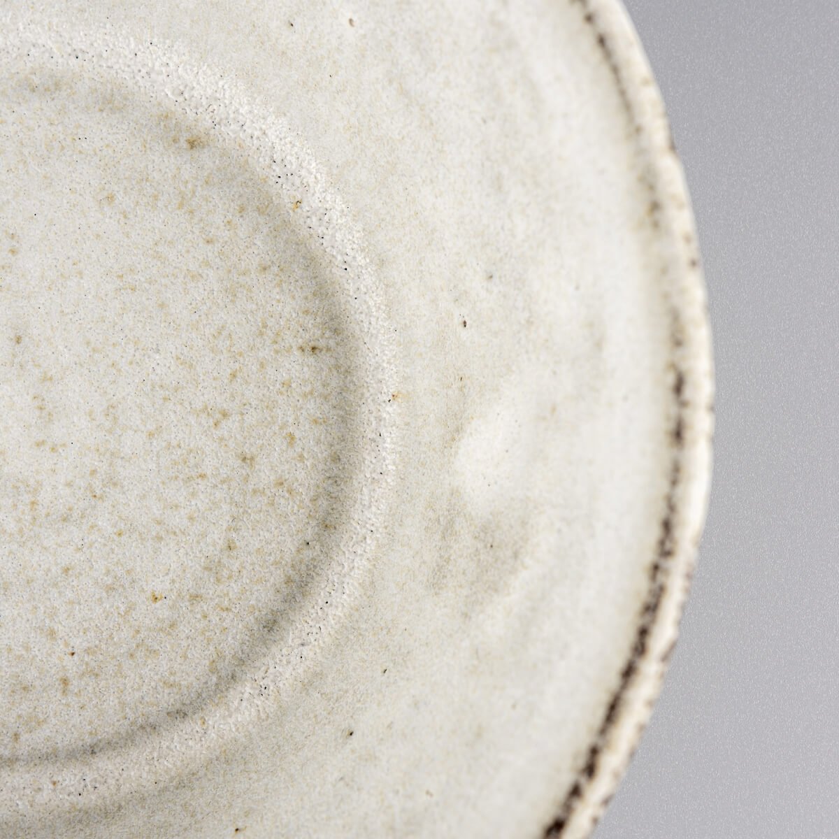 Close-up of pottery bowl rim showing natural speckling and handmade character.