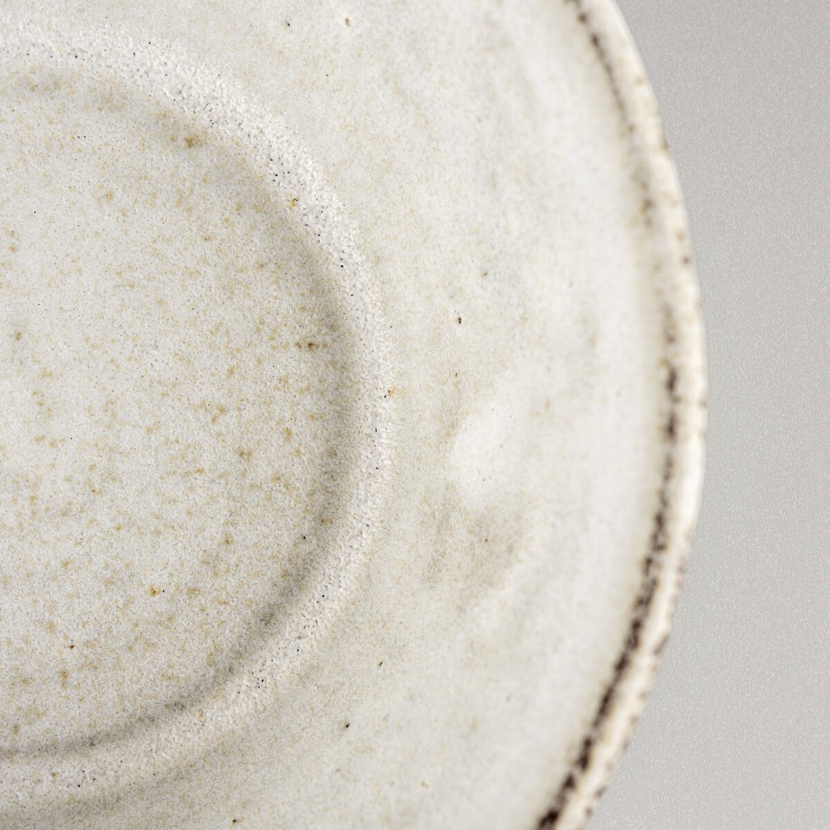 Close-up of pottery bowl rim showing natural speckling and handmade character.