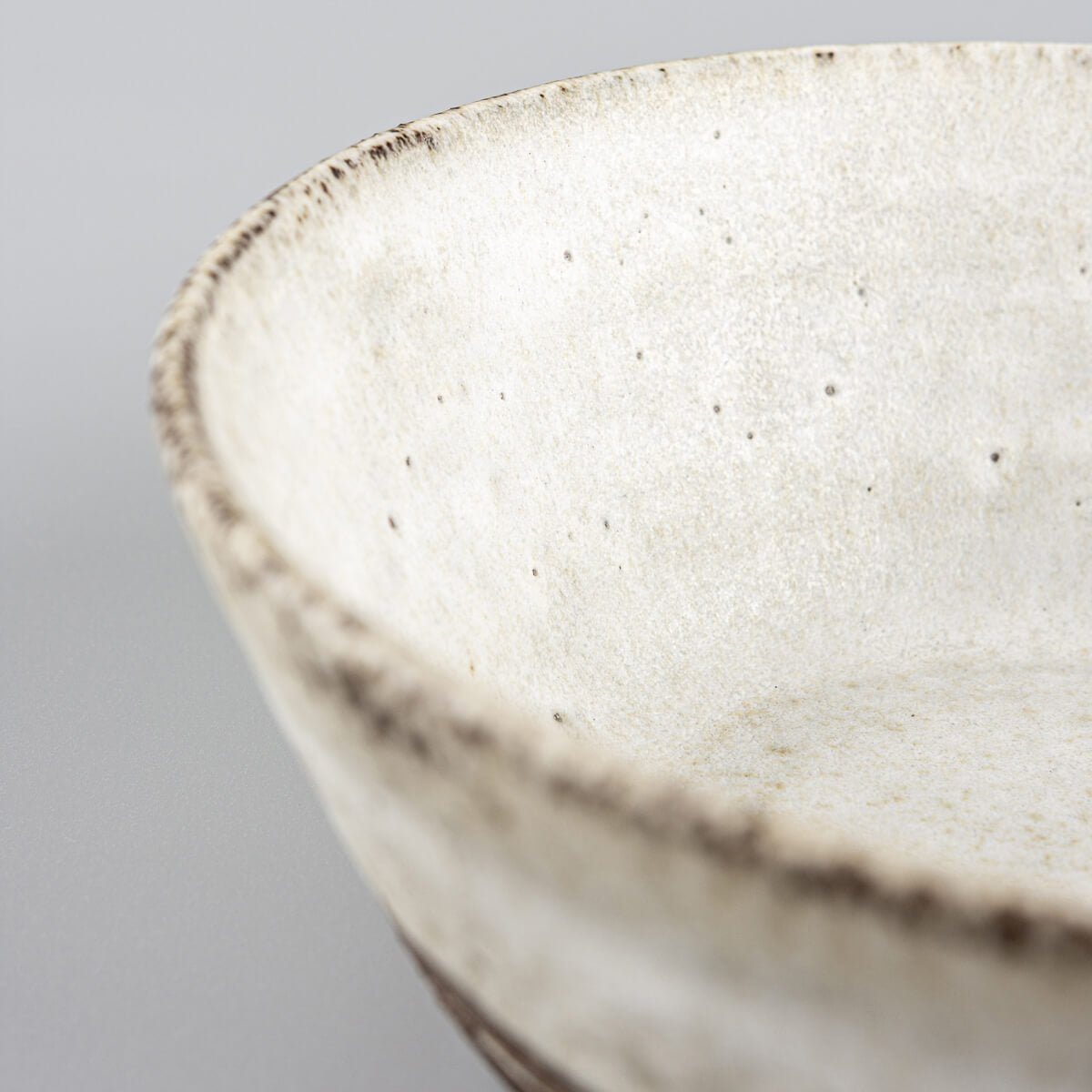 Profile view of rustic handmade bowl blending matte glaze and raw clay.