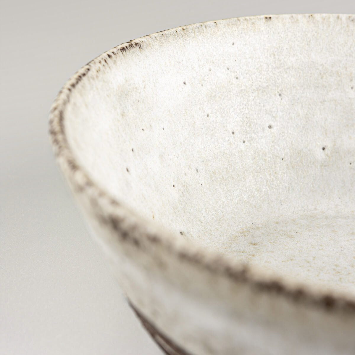 Profile view of rustic handmade bowl blending matte glaze and raw clay.