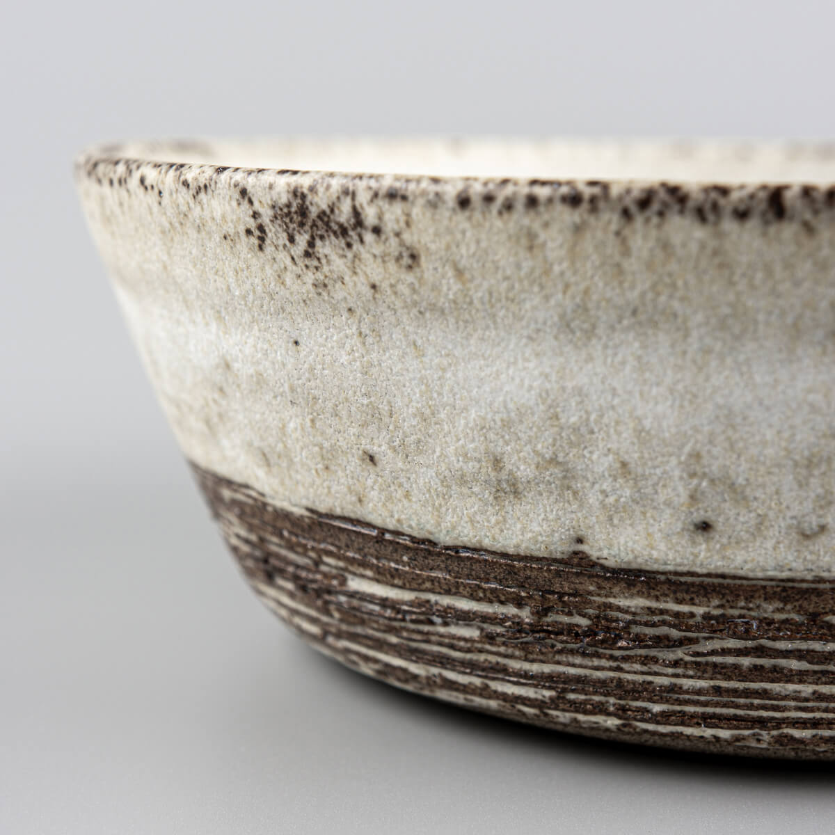 Diagonal shot highlighting hand-carved base and smooth upper section of bowl.