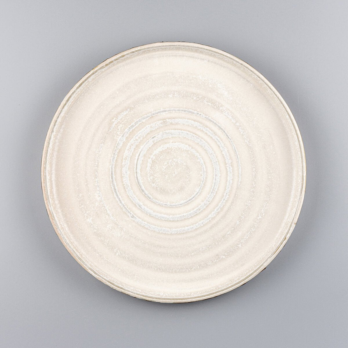 Handcrafted pottery dinner plate with spiral center and matte white glaze for fine dining presentation.