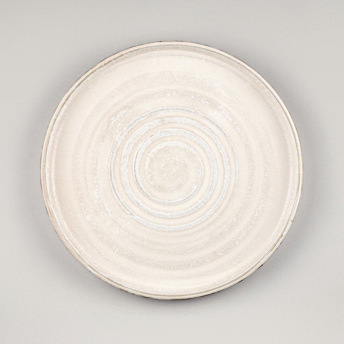 Handcrafted pottery dinner plate with spiral center and matte white glaze for fine dining presentation.