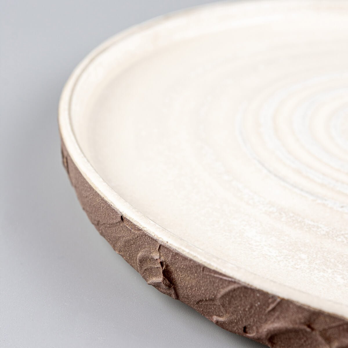 Rustic pottery dinner plate with earthy exterior and refined matte white glazed surface.