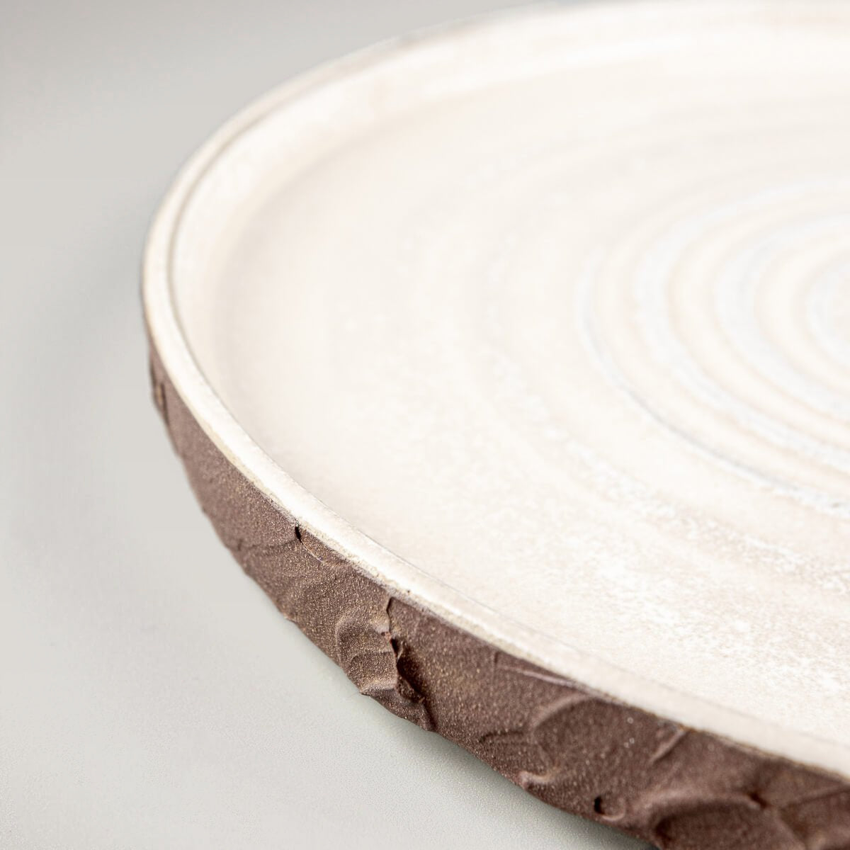 Rustic pottery dinner plate with earthy exterior and refined matte white glazed surface.