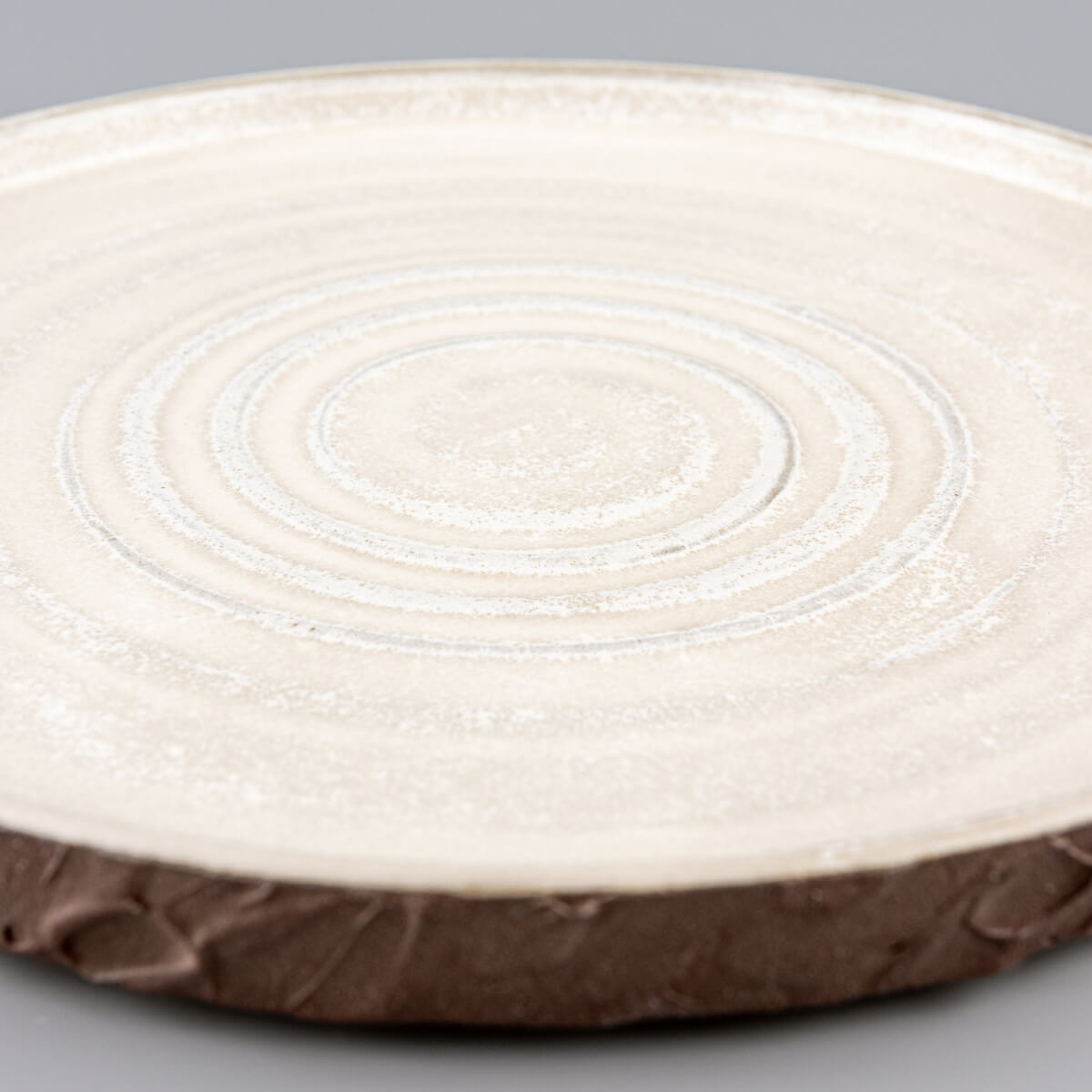 Handmade ceramic plate with low curved edges, ideal for boutique hotel dining settings.