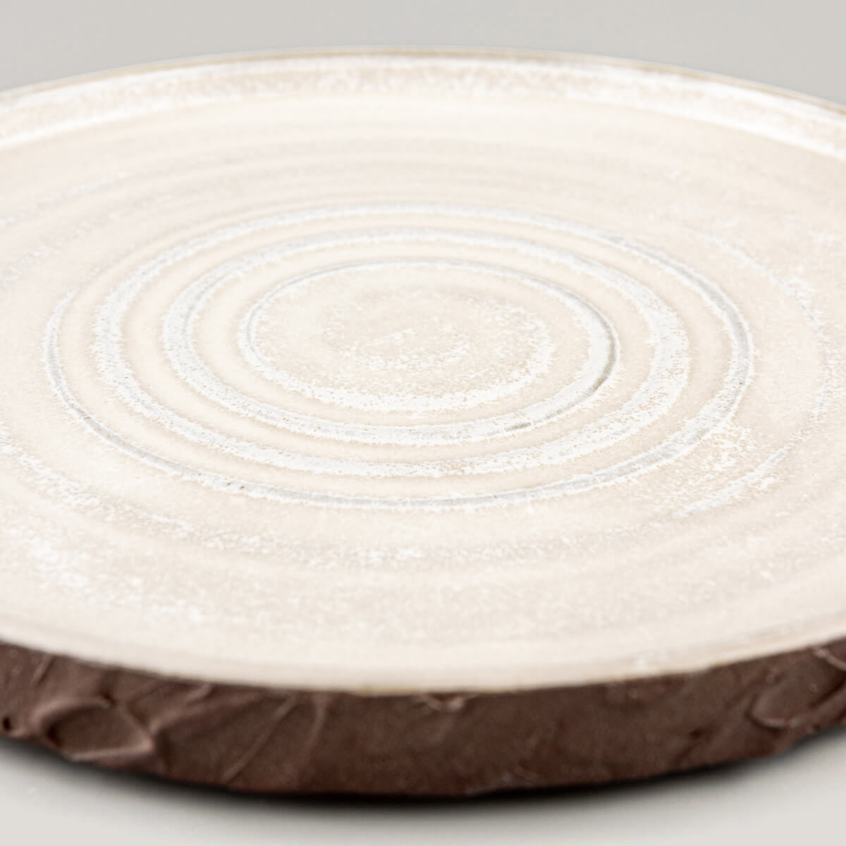 Handmade ceramic plate with low curved edges, ideal for boutique hotel dining settings.