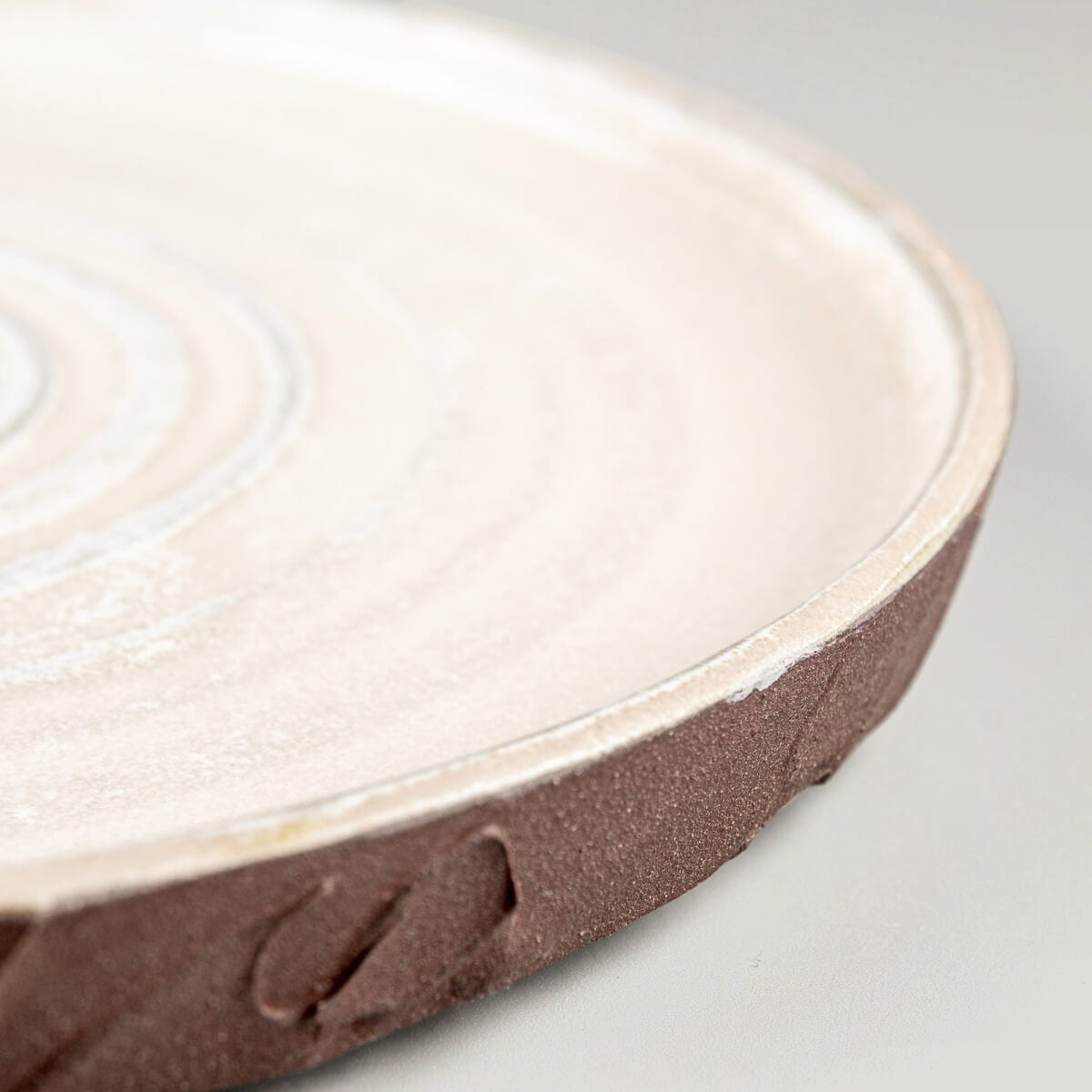 Side profile of handcrafted stoneware plate with spiral center and earthy exterior finish.