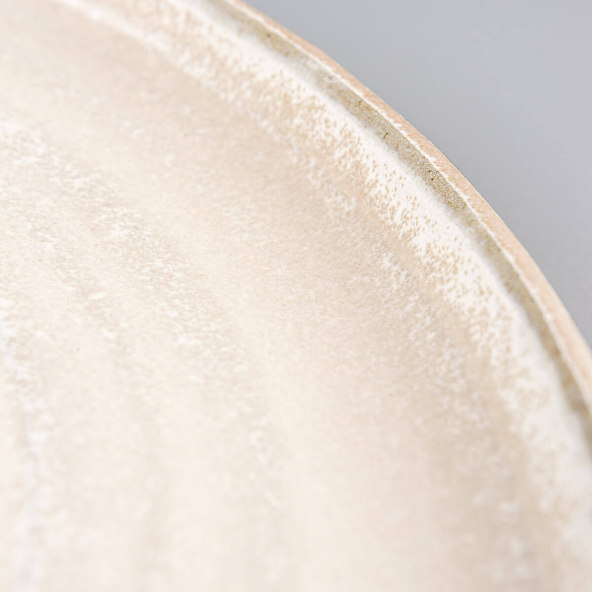 Pottery dinner plate with textured exterior and minimalist white glazed interior for modern dining.