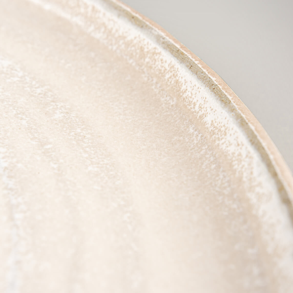 Pottery dinner plate with textured exterior and minimalist white glazed interior for modern dining.