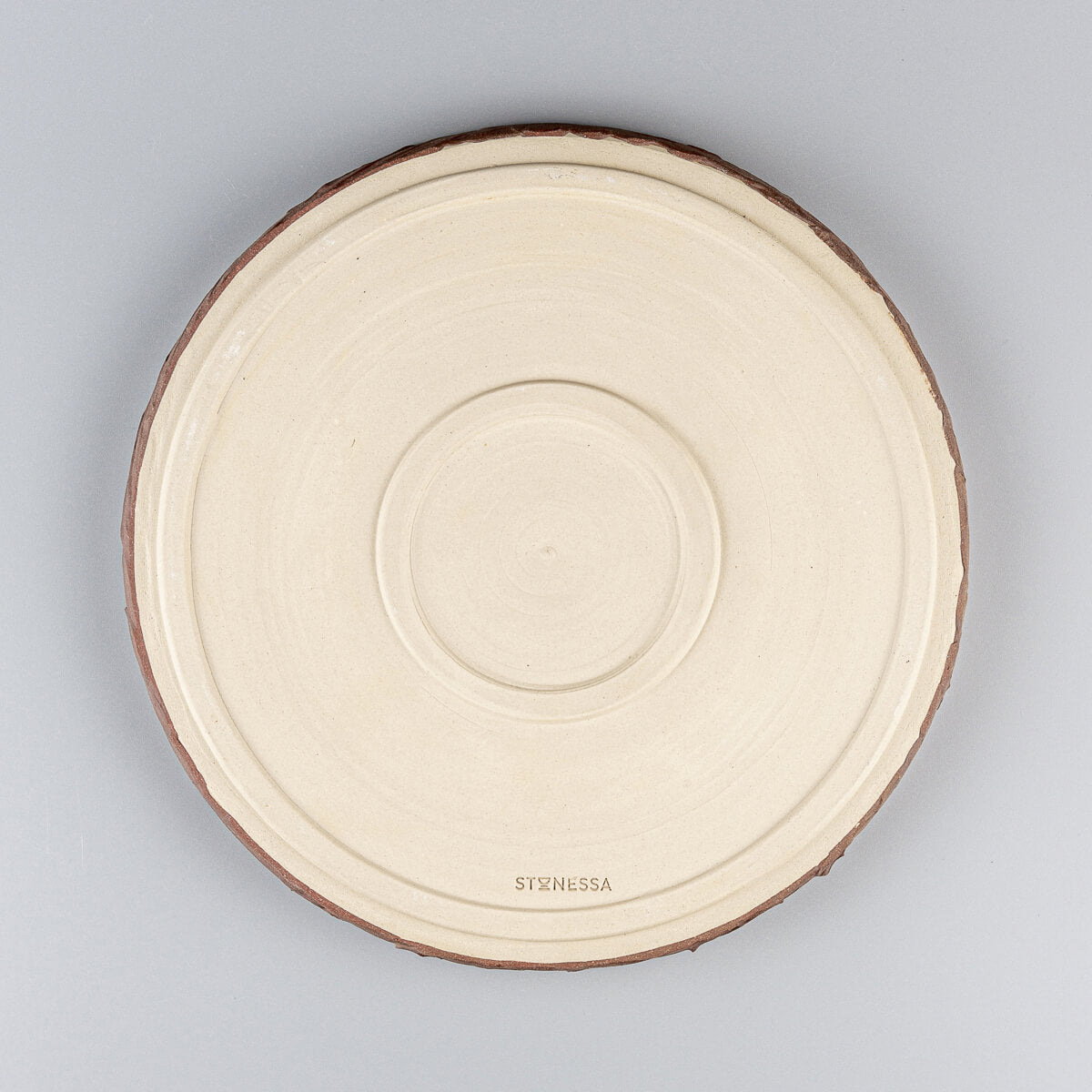 Handcrafted pottery dinner plate base with unglazed finish and Stonessa maker’s mark for artisanal authenticity.