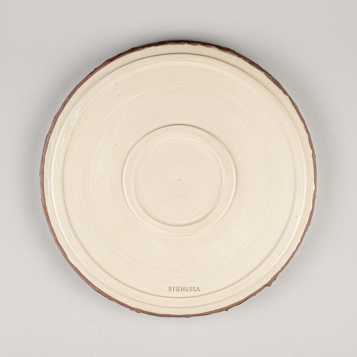 Handcrafted pottery dinner plate base with unglazed finish and Stonessa maker’s mark for artisanal authenticity.