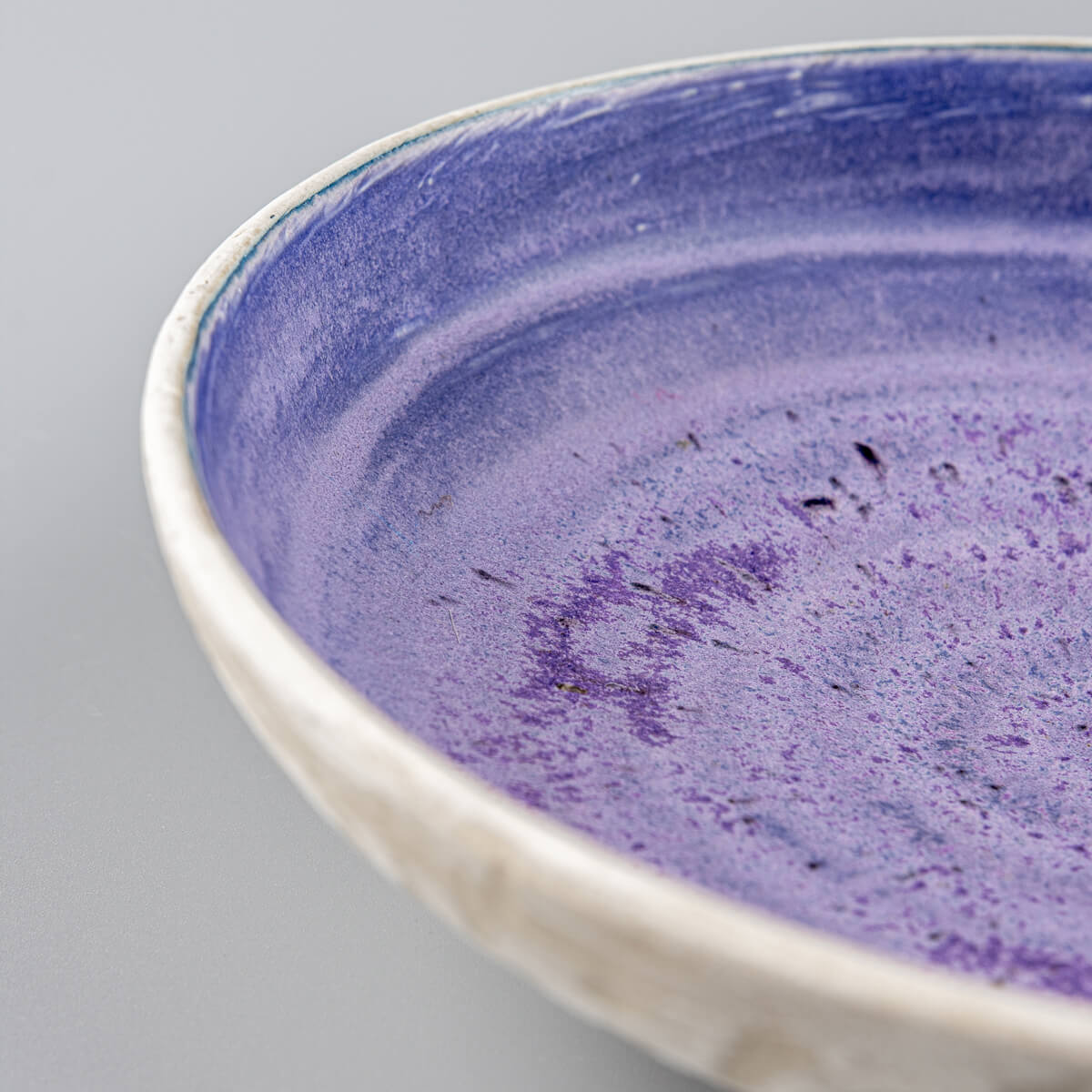 Detail of rounded rim and glaze transitions on artisan-crafted pottery bowl.