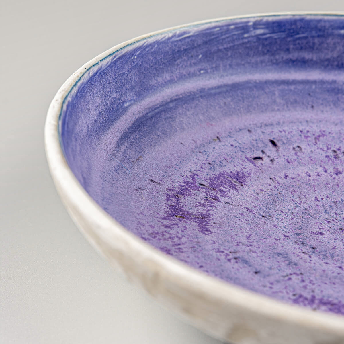 Detail of rounded rim and glaze transitions on artisan-crafted pottery bowl.