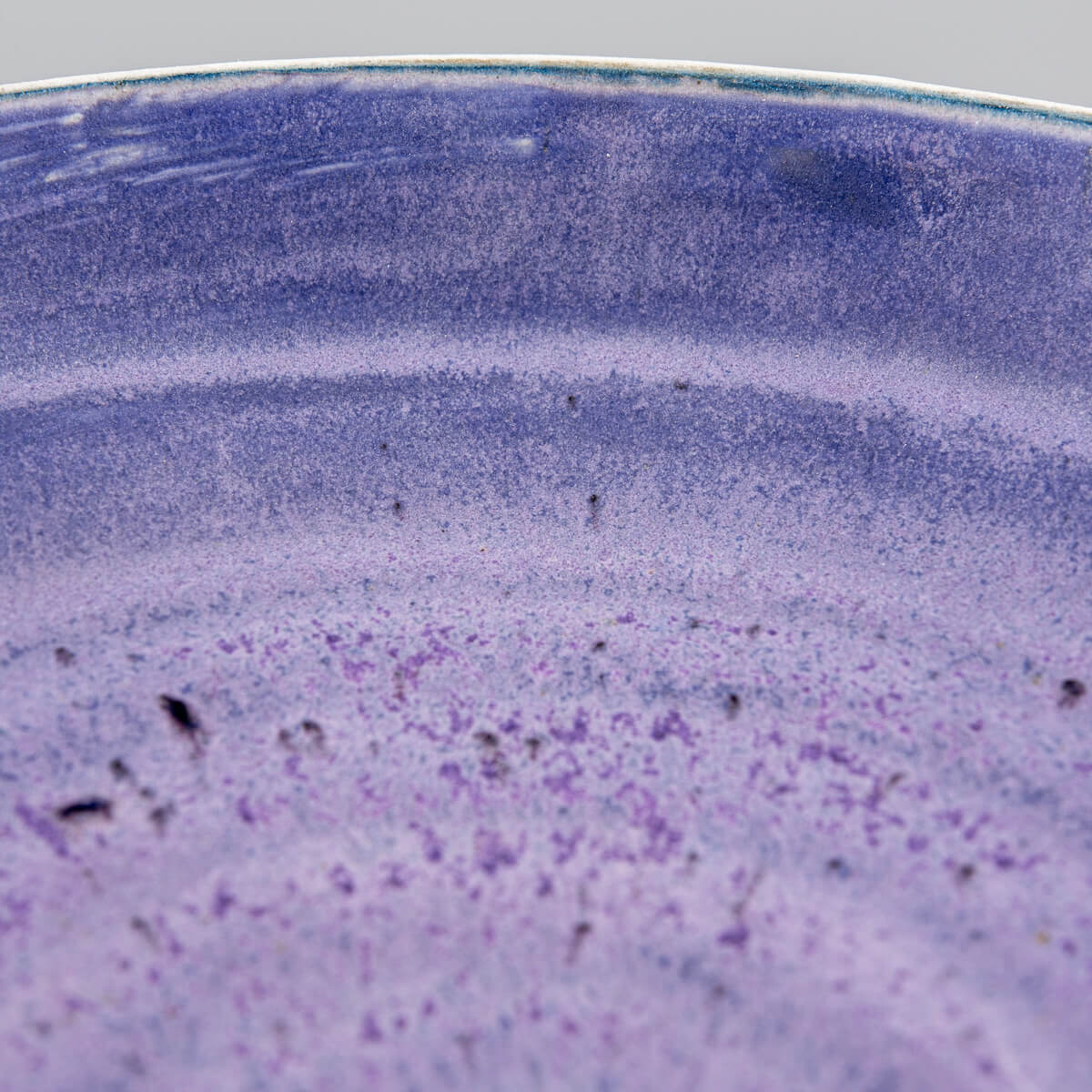 Macro of surface texture showing matte purple glaze with subtle brushwork.