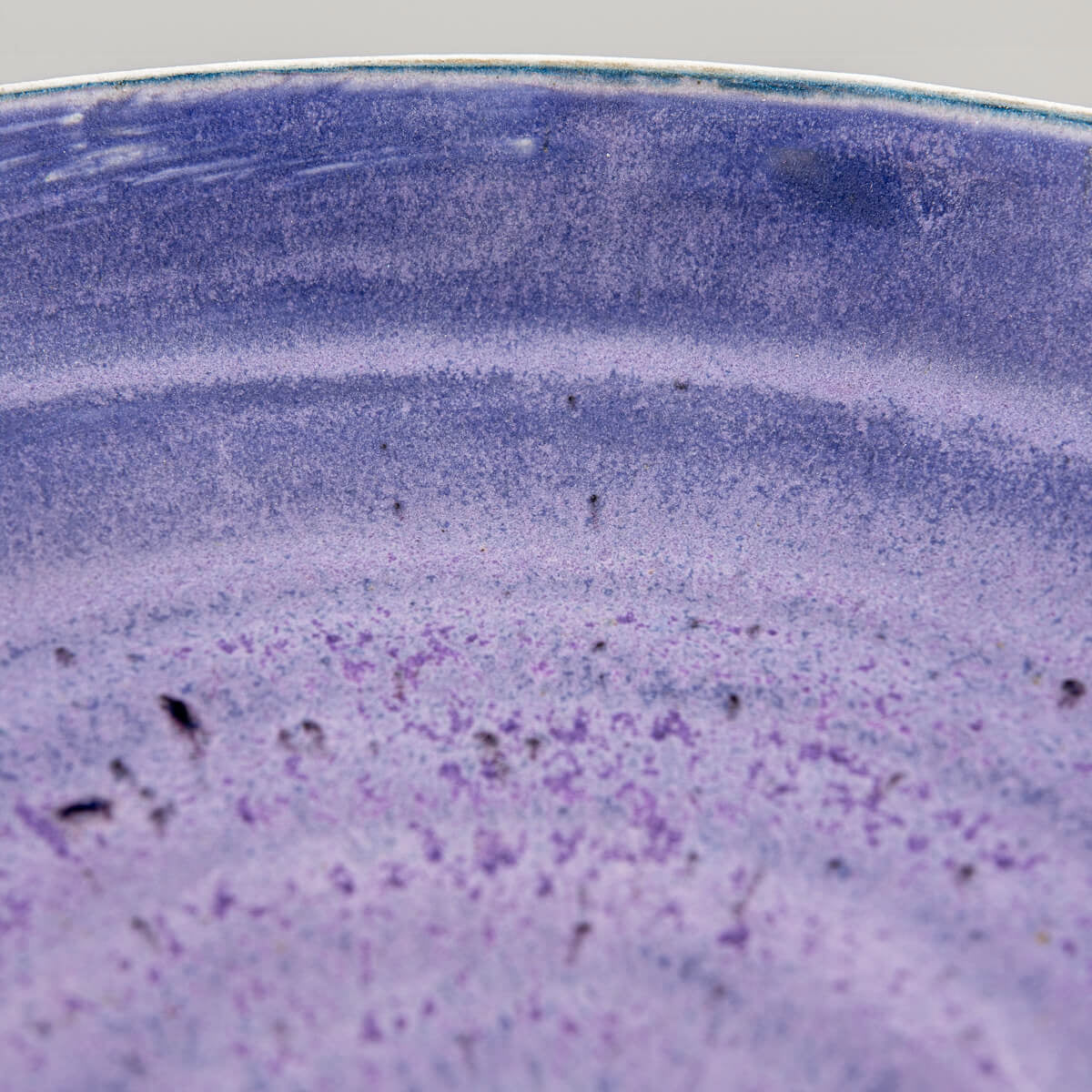 Macro of surface texture showing matte purple glaze with subtle brushwork.