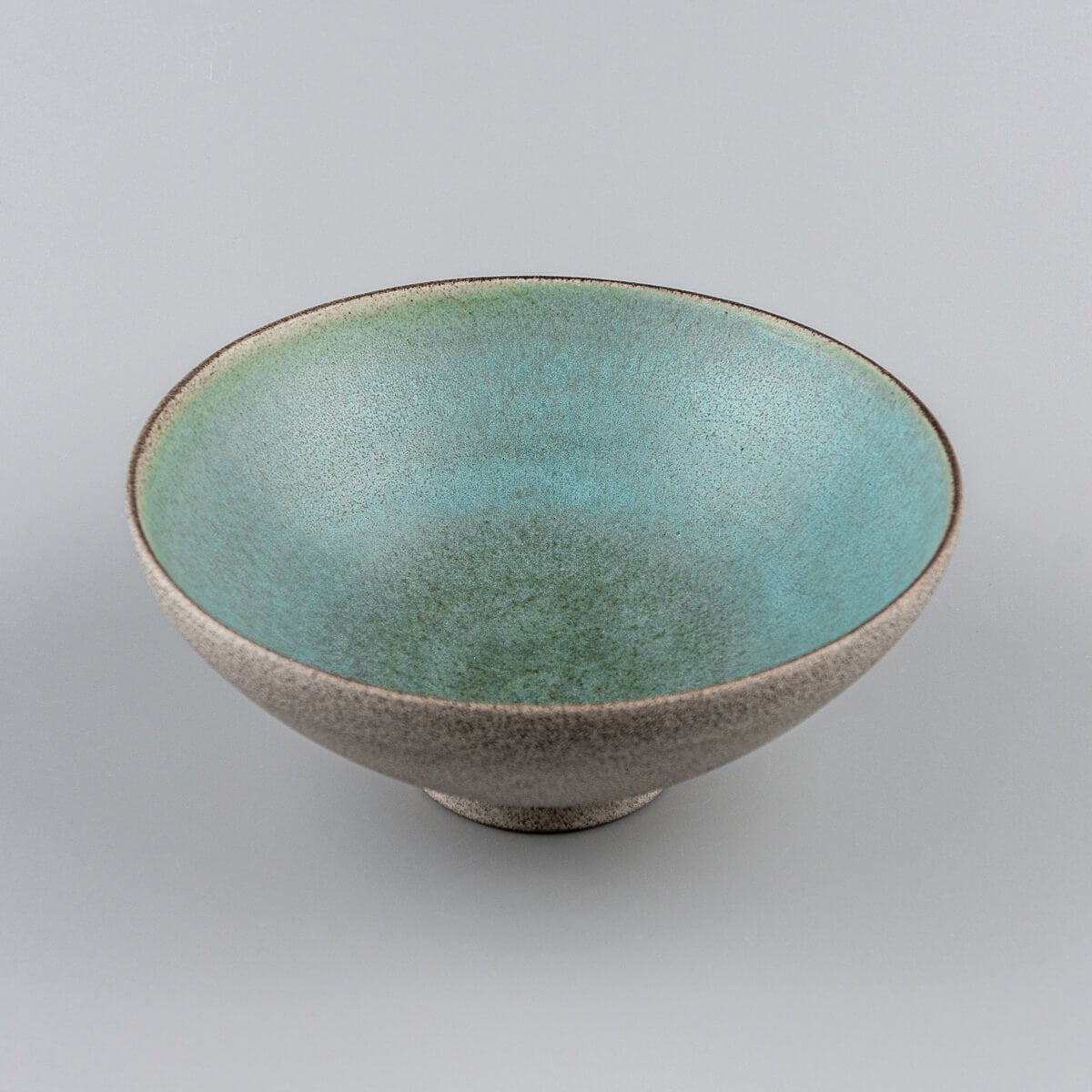 Symmetrical top view of turquoise-glazed ceramic bowl with artisanal details.