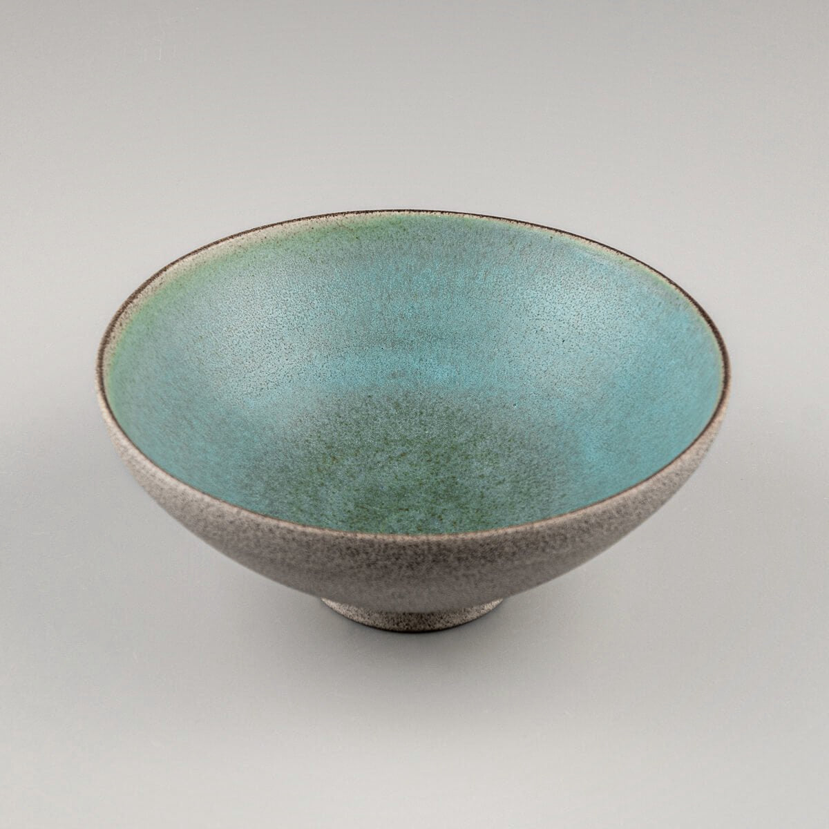 Symmetrical top view of turquoise-glazed ceramic bowl with artisanal details.
