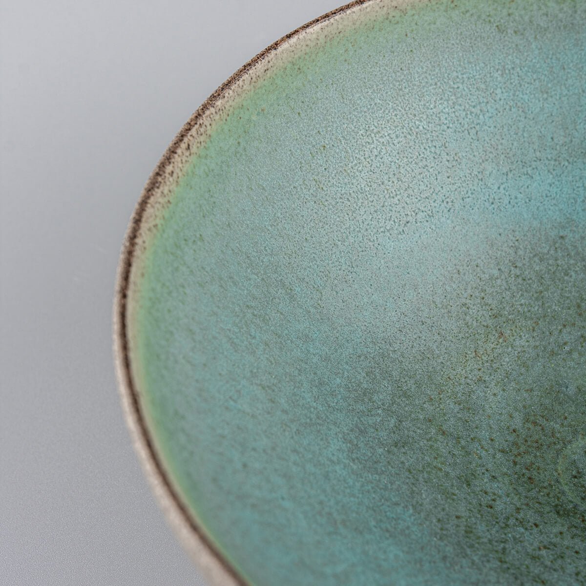Detail shot of curved rim edge with raw stoneware and fine glaze boundary.