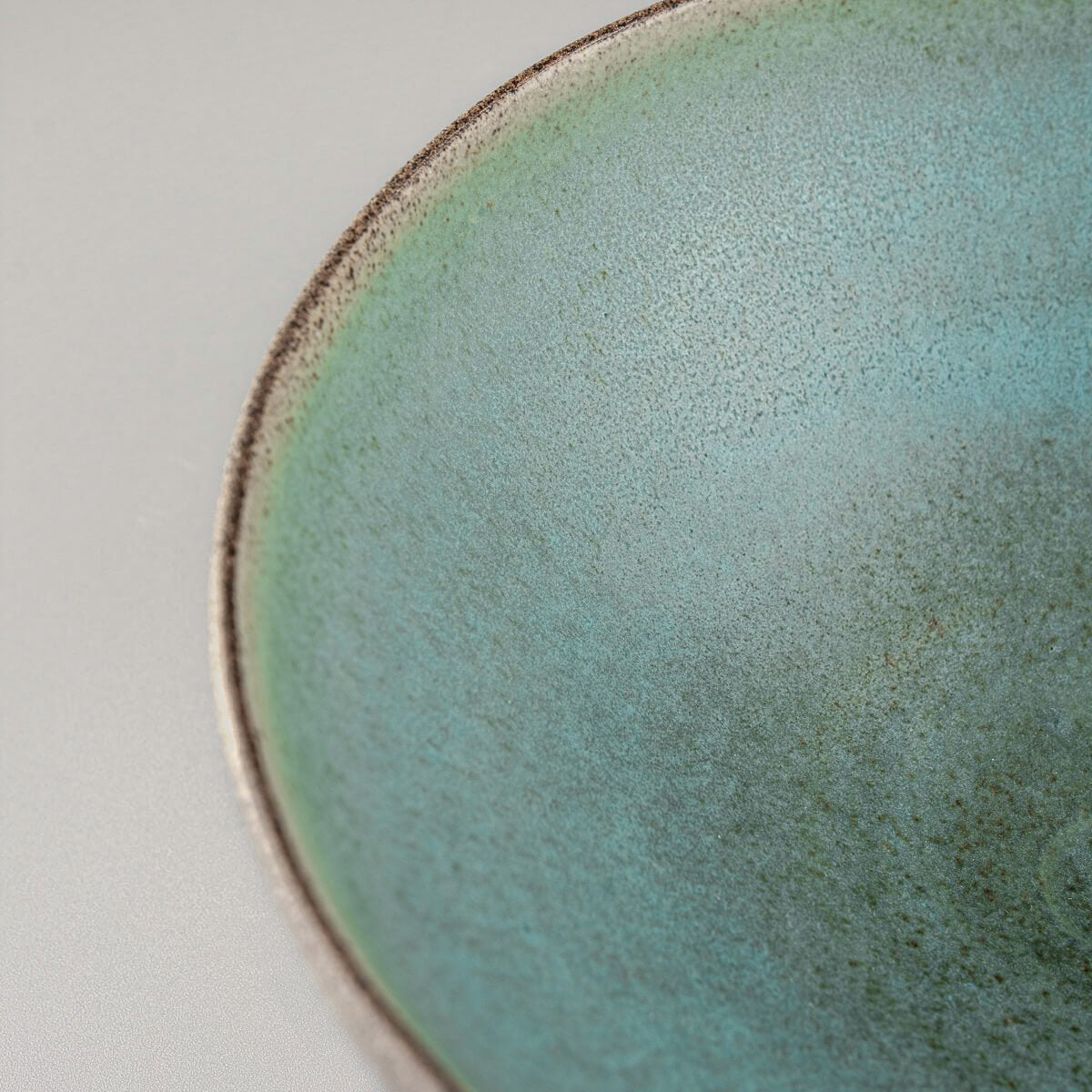 Detail shot of curved rim edge with raw stoneware and fine glaze boundary.