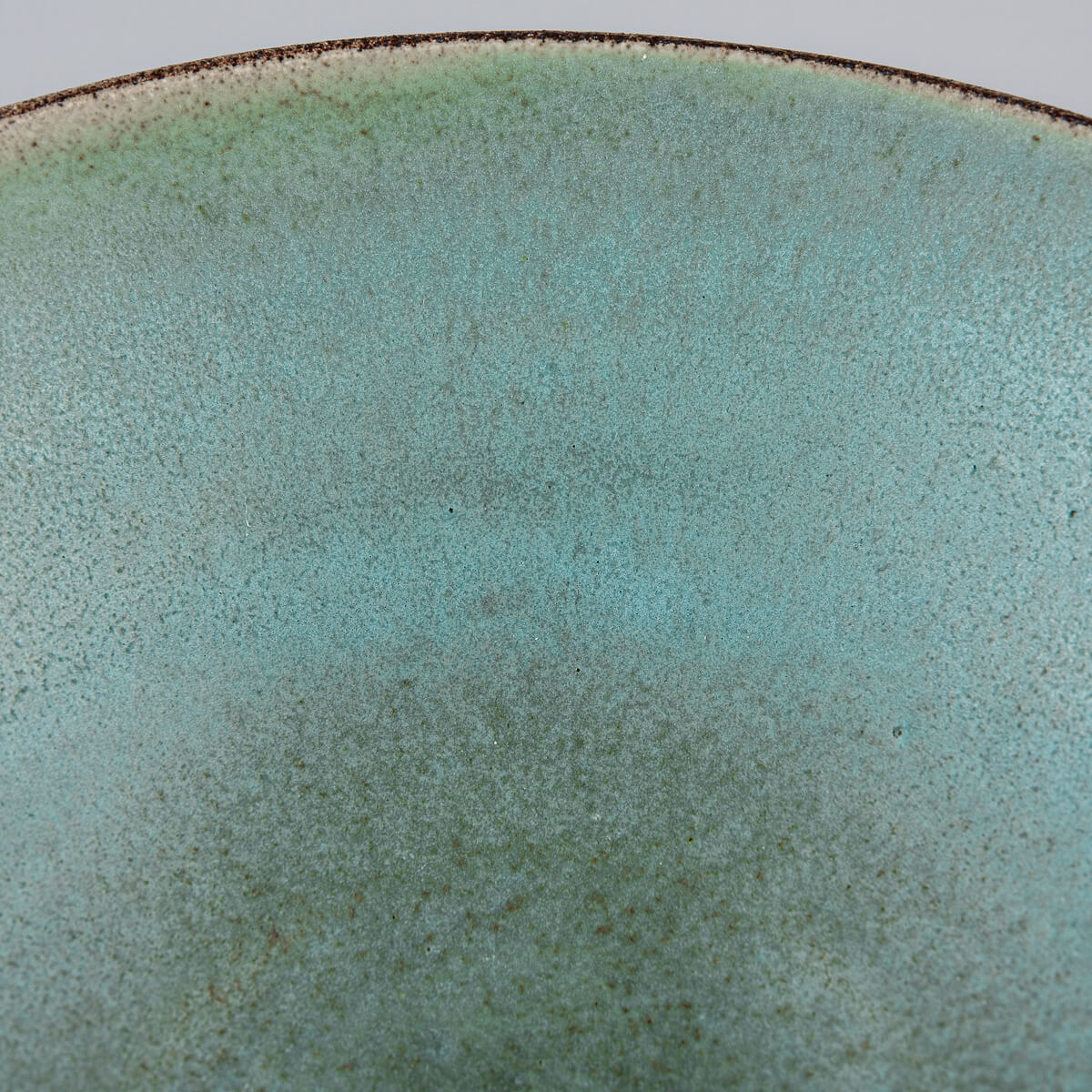 Macro image of glaze pattern inside handmade bowl with crater-like textures.