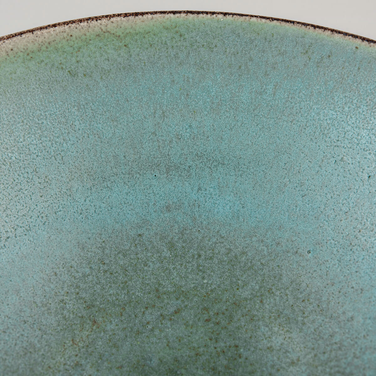 Macro image of glaze pattern inside handmade bowl with crater-like textures.