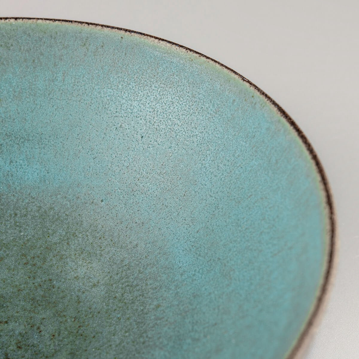 Close-up showing deep aqua tones and handcrafted brush marks on ceramic.