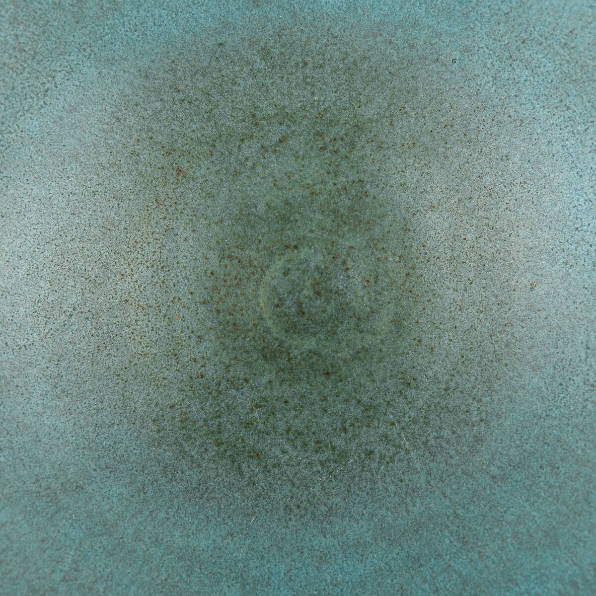 Top-down view of handmade ceramic bowl with turquoise glaze and artisan texture.