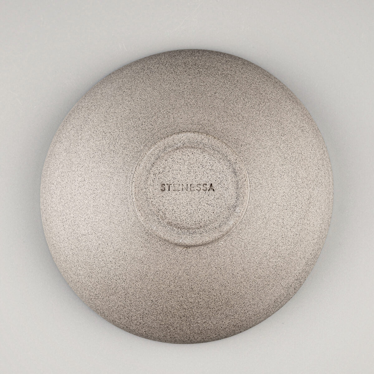Underside of a handmade ceramic bowl with potter’s mark and natural clay tone.