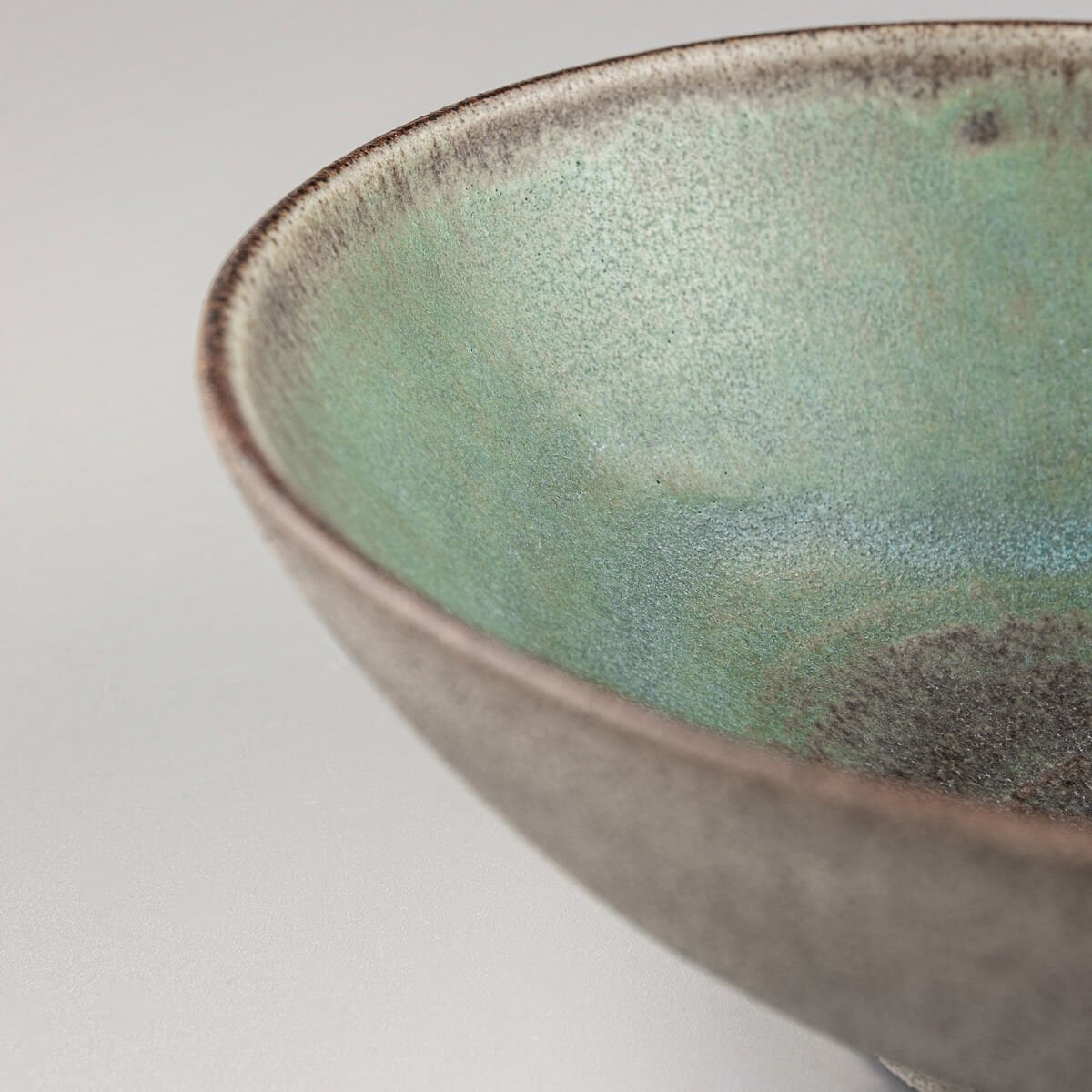Interior view of a handmade bowl showcasing artisanal green glaze and pottery detail.