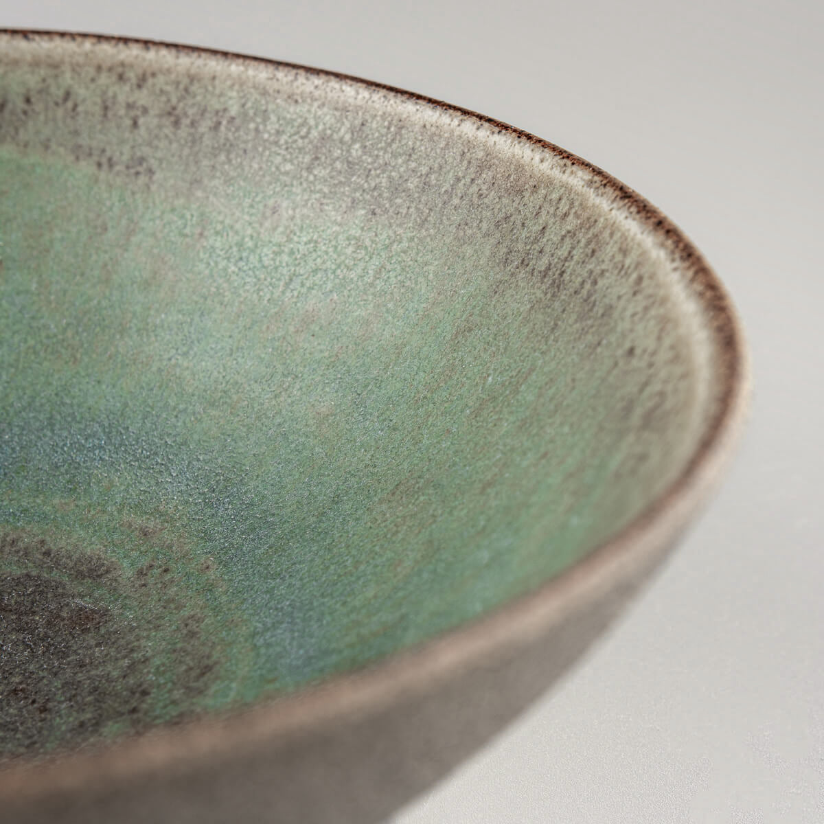 Angled detail of a bowl rim highlighting glaze transition and clay texture.