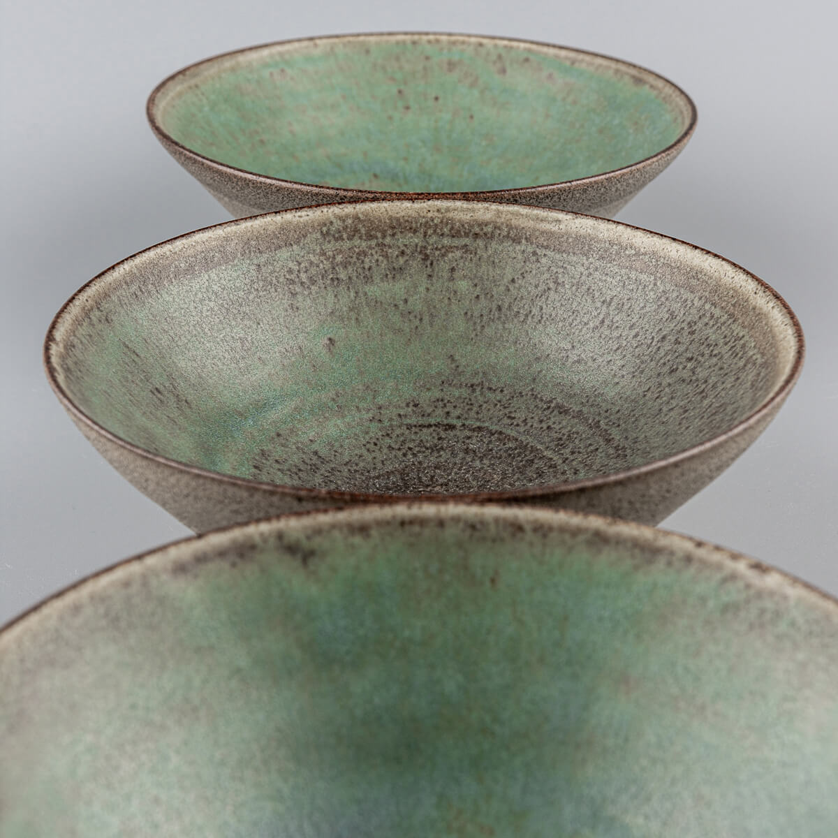 Stacked handmade bowls with matte glaze interiors and raw clay exteriors.