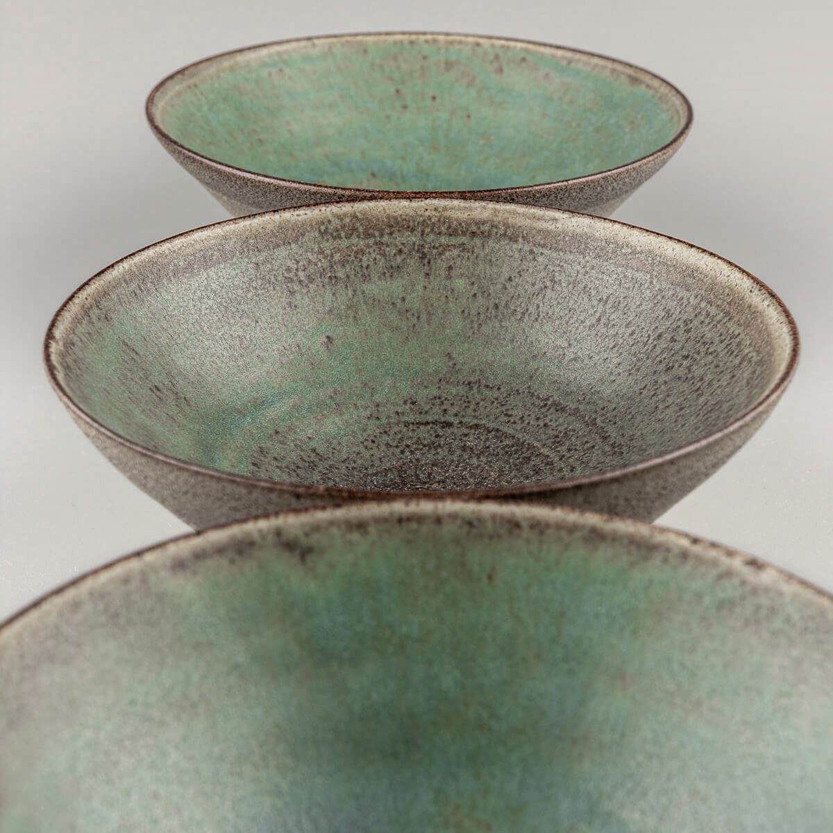 Stacked handmade bowls with matte glaze interiors and raw clay exteriors.